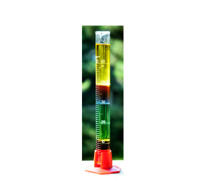 Un cilindro graduado que contiene varias sustancias químicas líquidas de colores con diferentes densidad